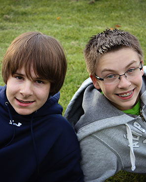 Two young patients with braces smiling outdoors